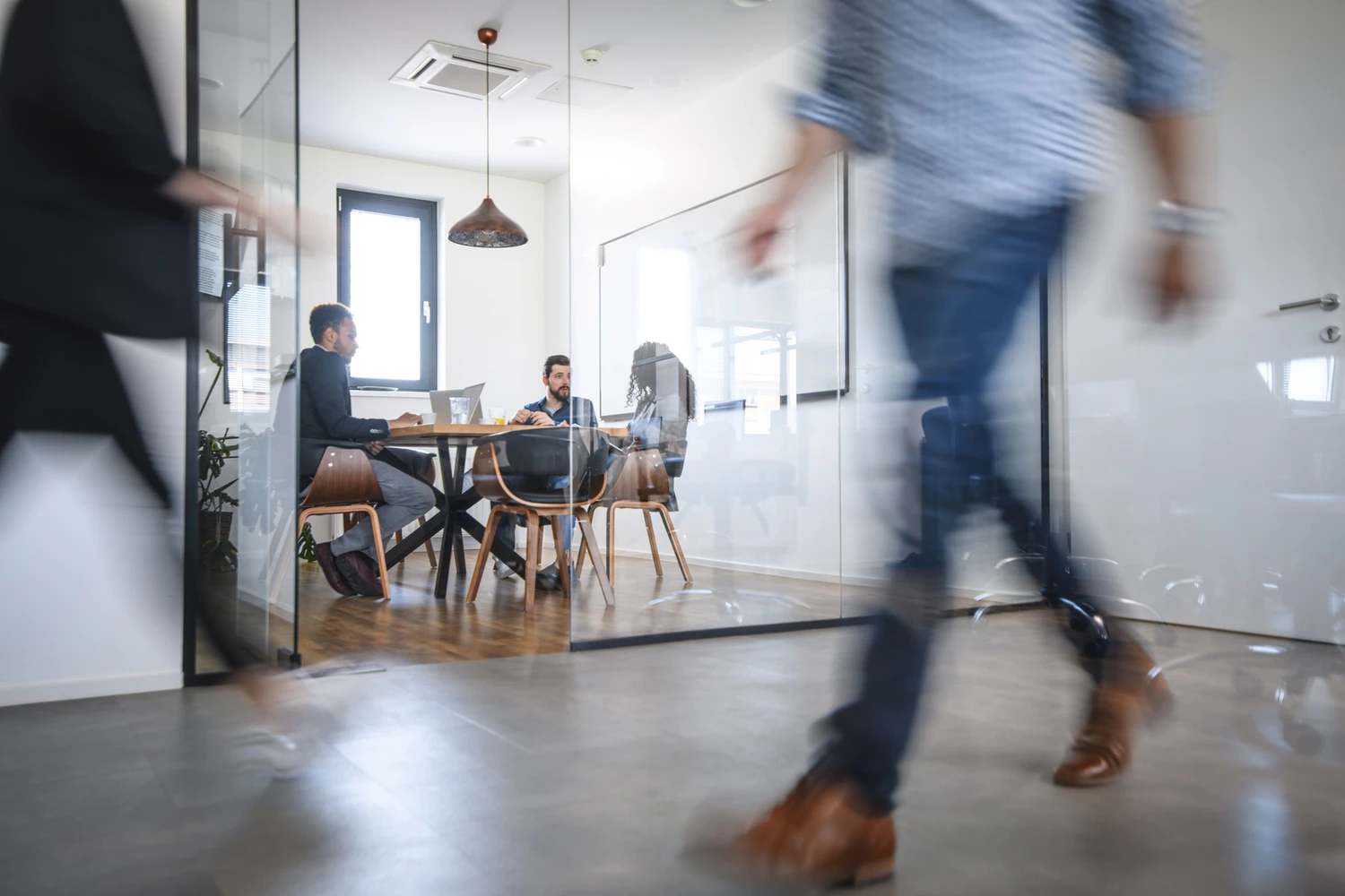 Man walking in an office with people attending a meeting